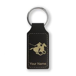 May include: Black leather keychain with a gold silhouette of a polo player on a horse. The keychain has a stitched border and the text "Your Name" is engraved below the image.