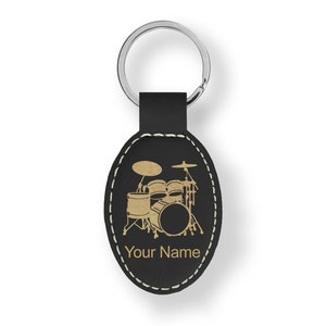 May include: Black leather oval keychain with a gold drum set silhouette and the text "Your Name".