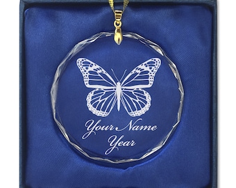 May include: A clear glass ornament with a butterfly design and the text "Your Name Year" engraved on it. The ornament is in a blue velvet box with a gold ribbon.