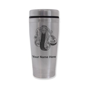 May include: A stainless steel travel mug with a black cobra design and the text "Your Name Here". The mug has a black lid and a silver body with horizontal grooves near the bottom.