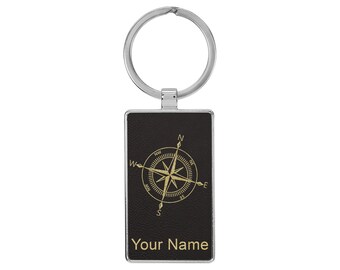 Peut inclure: Un porte-clés en cuir noir avec un motif de boussole doré et le texte "Your Name".