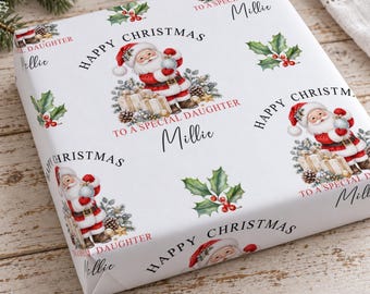 May include: White wrapping paper featuring a repeating pattern of Santa Claus holding a silver ornament, holly leaves with red berries, and pinecones. The text reads Happy Christmas, To A Special Daughter, and the name Millie in black script.