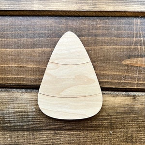 May include: A wooden cutout of a candy corn, a traditional Halloween treat. The cutout is unpainted and ready to be decorated.