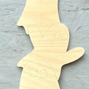 May include: Three wooden ghost cutouts in varying sizes, arranged vertically. Each ghost has simple, drawn-on eyes. The wood has a natural, light color, and the cutouts are unpainted, ready for customization. A hole is drilled at the top of the largest ghost.