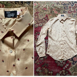 May include: A beige long-sleeved shirt with a geometric pattern in black and red. The shirt has a button-up front and a collared neckline. The label on the shirt reads "Tucci".
