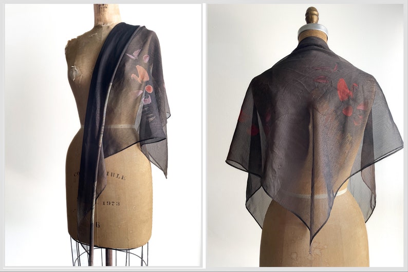 May include: A sheer black scarf with a floral print in shades of red, pink, and brown. The scarf is draped over a dress form.
