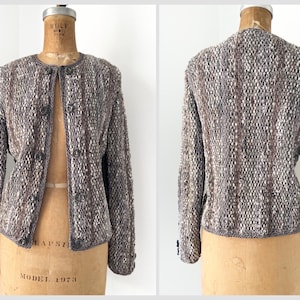 May include: A brown and white tweed jacket with a button closure. The jacket has a fitted silhouette and long sleeves.