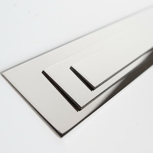 May include: Three silver metal strips of varying lengths, stacked on top of each other.