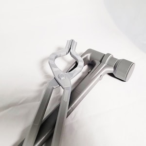 Puede incluir: Un martillo de metal plateado y unas pinzas de metal plateado con un agarre texturizado.