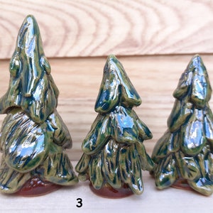 Puede incluir: Tres &aacute;rboles de pino de cer&aacute;mica de diferentes tama&ntilde;os, con un esmalte verde y marr&oacute;n. Los &aacute;rboles est&aacute;n dispuestos de mayor a menor, con el &aacute;rbol m&aacute;s grande a la izquierda y el m&aacute;s peque&ntilde;o a la derecha. Los &aacute;rboles est&aacute;n todos sobre una superficie de madera. El n&uacute;mero "3" est&aacute; escrito en la superficie delante de los &aacute;rboles.