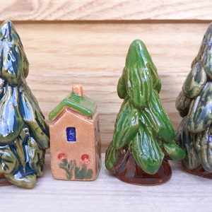 Puede incluir: Cuatro figuritas de cer&aacute;mica, tres &aacute;rboles verdes y una peque&ntilde;a casa marr&oacute;n con techo verde y ventana azul. Las figuritas est&aacute;n pintadas a mano y tienen un aspecto r&uacute;stico y vintage.