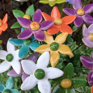 Op de afbeelding: Een boeket kleurrijke keramische bloemen met verschillende gekleurde centra. De bloemen zijn in een cluster gerangschikt en hebben een glanzende afwerking.
