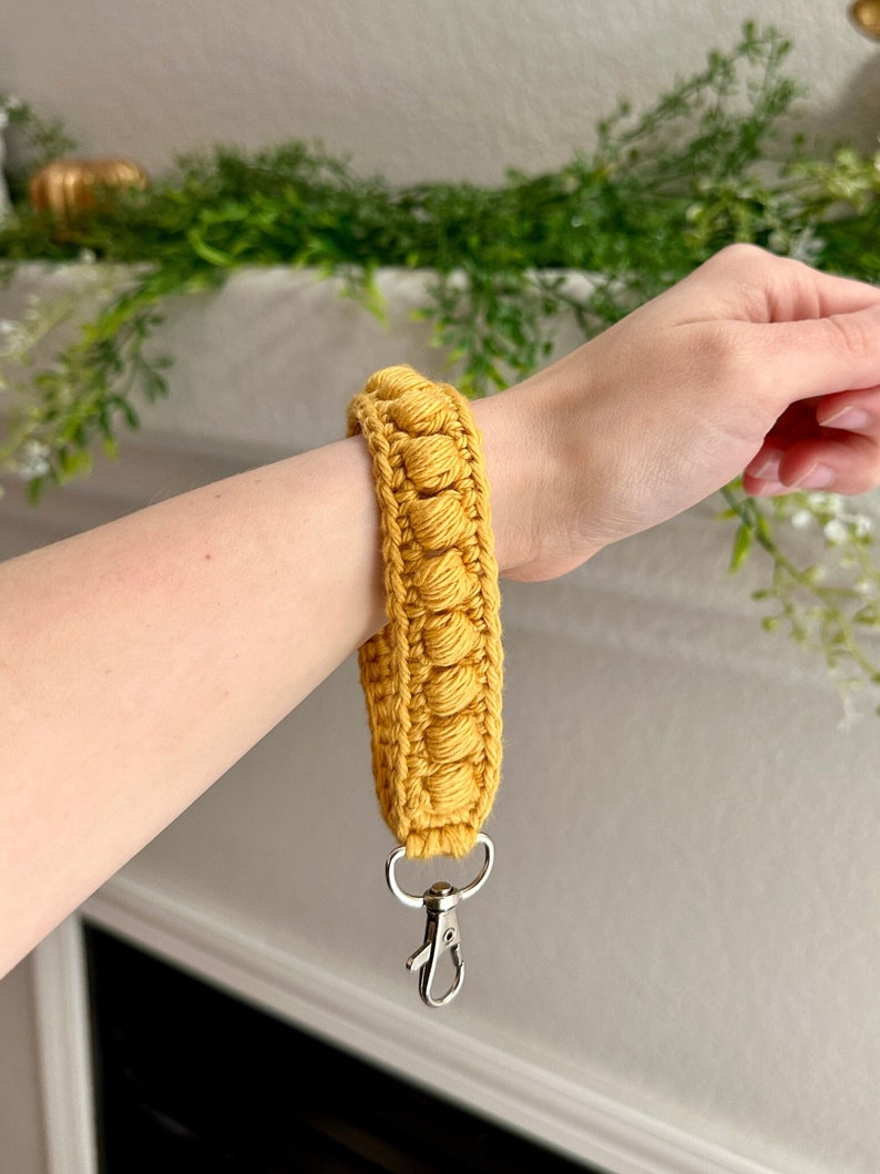 May include: A yellow crocheted keychain with a silver metal clasp.