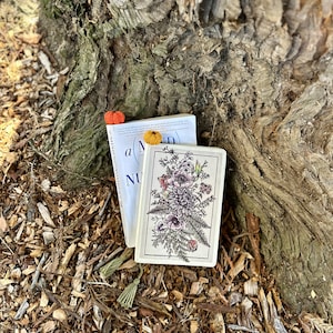 May include: Two books with floral designs and crocheted bookmarks. The book on top has the text "A Mind" and "NU" visible. The book on the bottom has a floral design with a fern and anemone.