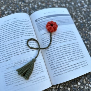 May include: An open book with a green tassel bookmark and a crocheted red flower bookmark. The book's pages feature text about memory techniques and learning.