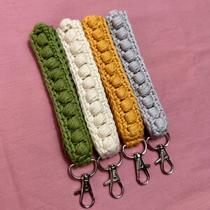 May include: Four crocheted keychains in green, white, yellow, and gray with silver key rings.