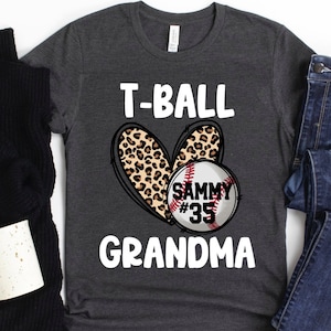 May include: Gray t-shirt with the text "T-BALL GRANDMA" and a leopard print heart with a baseball inside. The baseball has the text "SAMMY #35" on it.