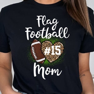 May include: Black t-shirt with a white graphic of a football in a heart with the text "Flag Football Mom" and the number "#15" on the football.