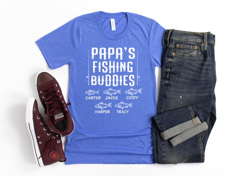 Puede incluir: Una camiseta azul con el texto "Papa's Fishing Buddies" y los nombres Carter, Jayce, Cody, Harper y Tracy impresos debajo. Los nombres est&aacute;n emparejados con un peque&ntilde;o gr&aacute;fico de pescado.