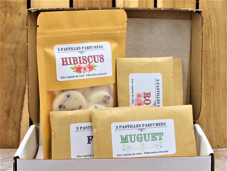 May include: A set of four brown paper bags containing scented wax melts. The bags are labeled with the scents "Hibiscus", "Rose", "Fig", and "Muguet".