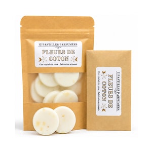 Może przedstawiać: Brązowa papierowa torebka zawierająca 12 białych wosków zapachowych z etykietą 12 PASTILLES PARFUMÉES FLEURS DE COTON oraz mniejsza papierowa koperta z 2 woskami z etykietą 2 PASTILLES PARFUMÉES FLEURS DE COTON z widocznymi okrągłymi krążkami wosku.