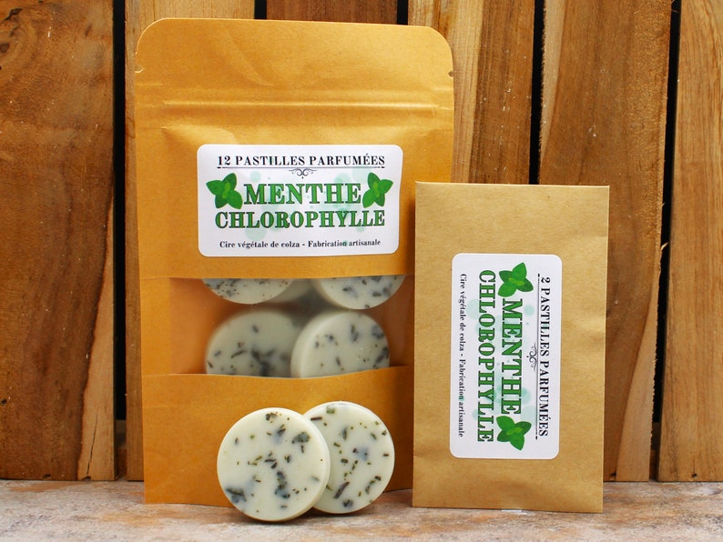 May include: Two brown paper bags with labels that read "12 Pastilles Parfum&eacute;es Menthe Chlorophylle Cire v&eacute;g&eacute;tale de colza - Fabrication artisanale" and "2 Pastilles Parfum&eacute;es Menthe Chlorophylle Cire v&eacute;g&eacute;tale de colza - Fabrication artisanale". The bags contain round, white wax melts with a green mint scent.