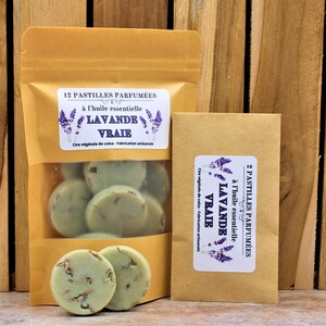 May include: Two brown paper bags with labels that read "12 Pastilles Parfum&eacute;es &agrave; l'huile essentielle Lavande Vraie Cire v&eacute;g&eacute;tale de colza - Fabrication artisanale" and "2 Pastilles Parfum&eacute;es &agrave; l'huile essentielle Lavande Vraie Cire v&eacute;g&eacute;tale de colza - Fabrication artisanale". The bags contain round, green wax melts.
