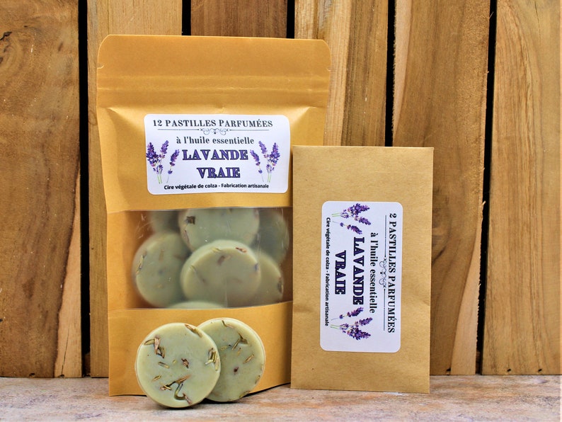 May include: Two brown paper bags with labels that read "12 Pastilles Parfum&eacute;es &agrave; l'huile essentielle Lavande Vraie Cire v&eacute;g&eacute;tale de colza - Fabrication artisanale" and "2 Pastilles Parfum&eacute;es &agrave; l'huile essentielle Lavande Vraie Cire v&eacute;g&eacute;tale de colza - Fabrication artisanale". The bags contain round, green wax melts.