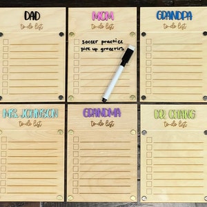 Pode incluir: Seis quadros de madeira para listas de tarefas com nomes diferentes escritos neles em letras coloridas. Os nomes s&atilde;o Pai, M&atilde;e, Av&ocirc;, Sra. Johnson, Av&oacute; e Dr. Chang. Cada quadro tem uma superf&iacute;cie de apagamento a seco e uma capa de pl&aacute;stico transparente.