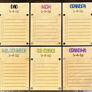Pode incluir: Seis quadros de madeira para listas de tarefas com nomes diferentes em cada um. Os nomes s&atilde;o "Pai", "M&atilde;e", "Av&ocirc;", "Sra. Johnson", "Dr. Chang" e "Av&oacute;". Cada quadro tem uma lista de tarefas com linhas em branco para escrever.