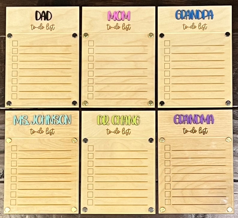 Pode incluir: Seis quadros de madeira para listas de tarefas com nomes diferentes em cada um. Os nomes s&atilde;o "Pai", "M&atilde;e", "Av&ocirc;", "Sra. Johnson", "Dr. Chang" e "Av&oacute;". Cada quadro tem uma lista de tarefas com linhas em branco para escrever.