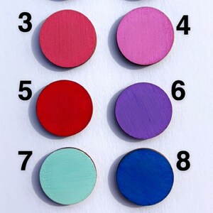 Pode incluir: Dez discos redondos de madeira pintados em diferentes cores, numerados de 1 a 10. As cores s&atilde;o preto, branco, rosa, vermelho, roxo, azul claro, azul escuro, verde e amarelo.