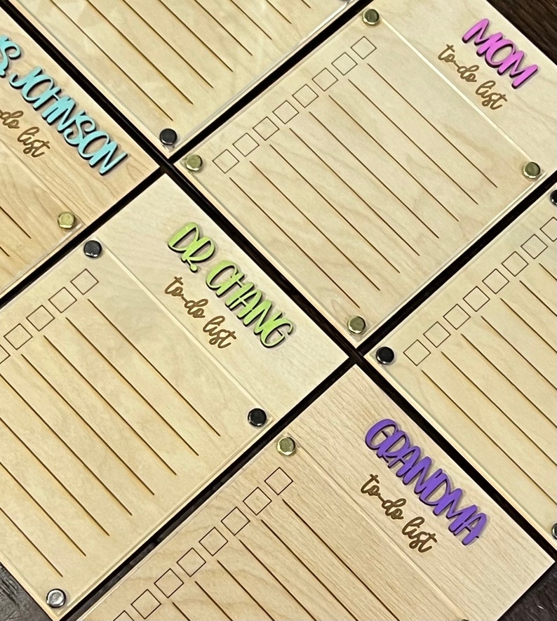 Pode incluir: Quatro quadros de madeira de lista de tarefas com nomes diferentes escritos neles em letras coloridas. Os nomes s&atilde;o M&atilde;e, Dr. Chang, Chinson e Av&oacute;. Cada quadro tem uma lista de caixas de sele&ccedil;&atilde;o.