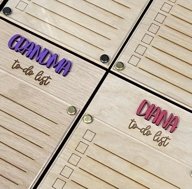 Pode incluir: Dois quadros de madeira de lista de tarefas pendentes com uma sobreposi&ccedil;&atilde;o de acr&iacute;lico transparente. O quadro superior tem o texto "GRANDMA to-do list" em letras roxas. O quadro inferior tem o texto "DIANA to-do list" em letras vermelhas.