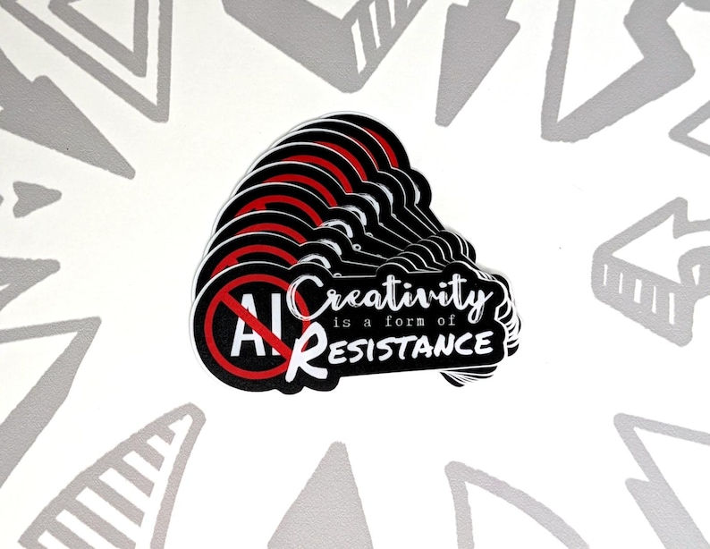 May include: A stack of black and white stickers with a red prohibition symbol over the letters "AI". The stickers have the text "Creativity is a form of RESISTANCE" in white. The background is white with gray arrow designs.