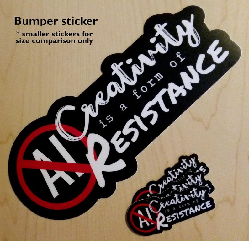 May include: Black bumper sticker with the text "Creativity is a form of RESISTANCE" in white script. The sticker also features a red circle with a line through the words "AI" in white. Smaller stickers with the same design are also present.