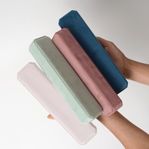 May include: Four velvet-lined boxes stacked on top of each other. The boxes are in shades of pink, green, and blue.