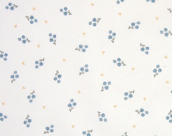 May include: White fabric with a repeating pattern of small blue flower clusters and tiny yellow dots.