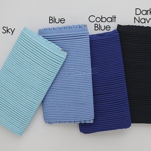 May include: Four samples of ribbed fabric in different shades of blue: sky blue, blue, cobalt blue, and dark navy.