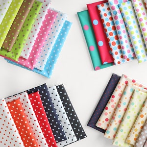 Op de afbeelding: Een verzameling kleurrijke stofstalen met stippen in verschillende kleuren, waaronder rood, oranje, geel, groen, blauw, roze en wit.