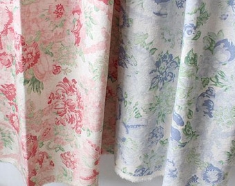 May include: Close-up of two floral fabric swatches. One features pink and red roses with green leaves on a cream background. The other has blue and green floral patterns on a white background. The fabrics are draped.