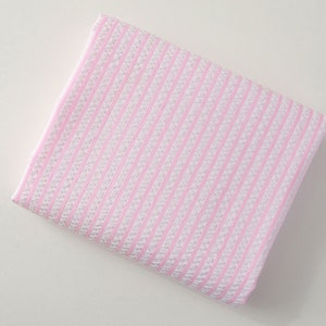 May include: A pink and white striped fabric with a textured surface.