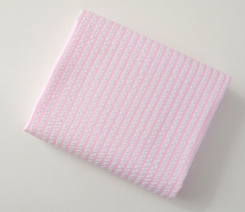 May include: A pink and white striped fabric with a textured surface.