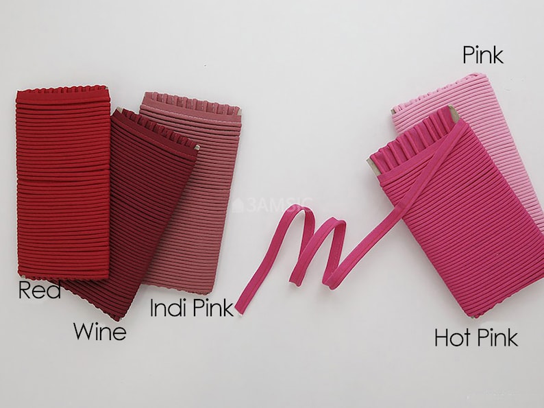 May include: Five different colors of ribbed elastic fabric, including red, wine, Indi Pink, pink, and hot pink. The fabric is folded and arranged in a row on a white surface.