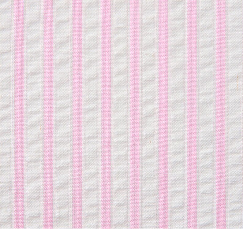 May include: White fabric with pink stripes. The fabric has a woven texture.