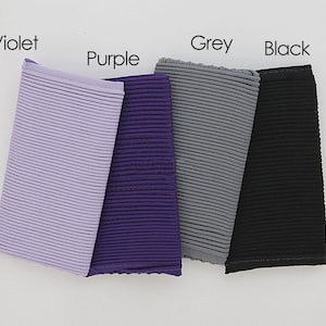 May include: Four fabric swatches in different colors: violet, purple, grey, and black. Each swatch has a ribbed texture.