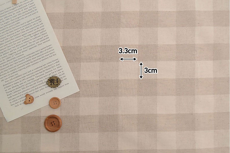 May include: Beige and white gingham fabric with a 3.3 inch by 3 inch square marked out. The fabric has a subtle texture.