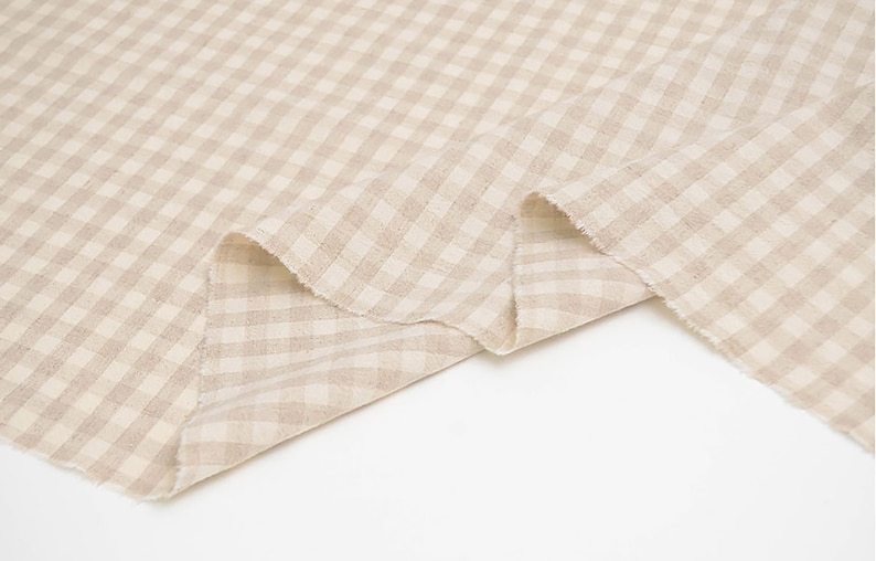 May include: Beige gingham fabric with a subtle texture. The fabric is folded in half and the edges are visible.