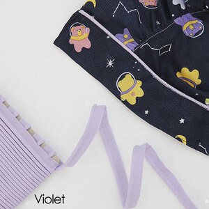 May include: A close-up of a purple fabric trim with a textured surface. The trim is folded and arranged in a wavy pattern. The word "Violet" is printed in black below the trim.