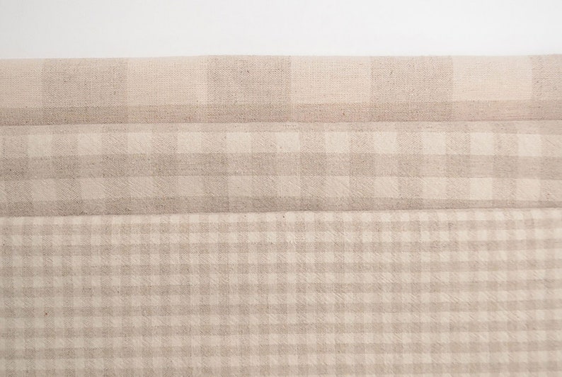 May include: Three layers of beige gingham fabric with a subtle texture. The fabric is folded in thirds, creating a layered effect.